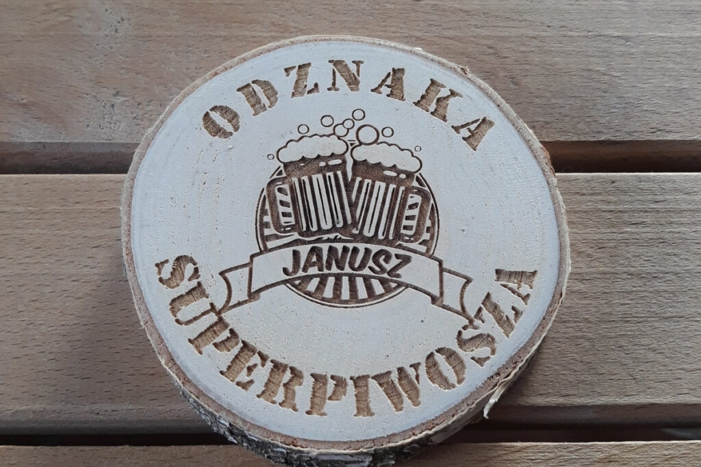 Drewniana podstawka pod piwo wykonana z naturalnego plastra brzozy z korą, z grawerem „Odznaka Superpiwosza”, motywem gwiazdy i kufla piwa, czysta powierzchnia bez osmaleń.