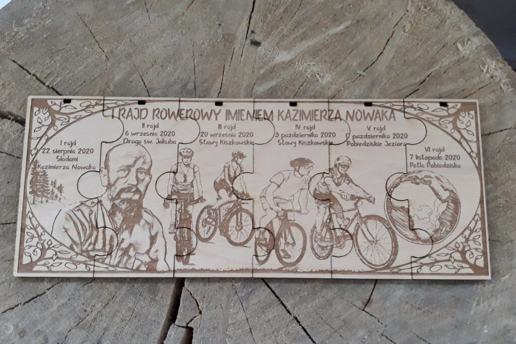 Zestaw sześciu drewnianych medali modułowych na rajd rowerowy, które po złożeniu tworzą prostokątną tabliczkę z grawerem kolarzy na trasie, logotypem wydarzenia i mapą, wykonany z jasnej brzozy bez śladów osmaleń.
