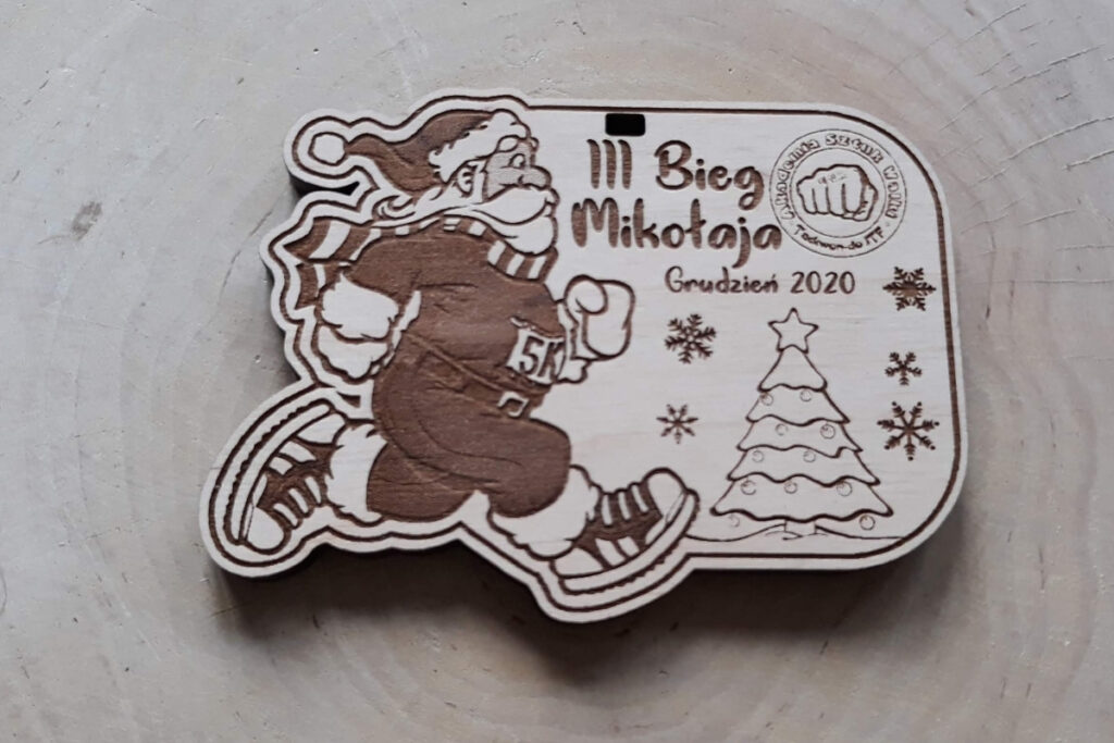 Nieregularnych kształtów drewniany medal na Bieg Mikołajów, z grawerem sympatycznego Świętego Mikołaja w pełnym biegu, wykonany z jasnej brzozy bez śladów dymu.