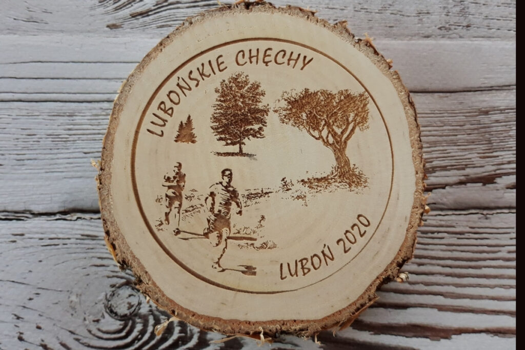 Drewniany medal na „Lubońskie Chechy” wykonany na naturalnym plastrze brzozy z korą, z grawerem logotypu wydarzenia, daty oraz biegacza, czysta powierzchnia bez osmaleń.