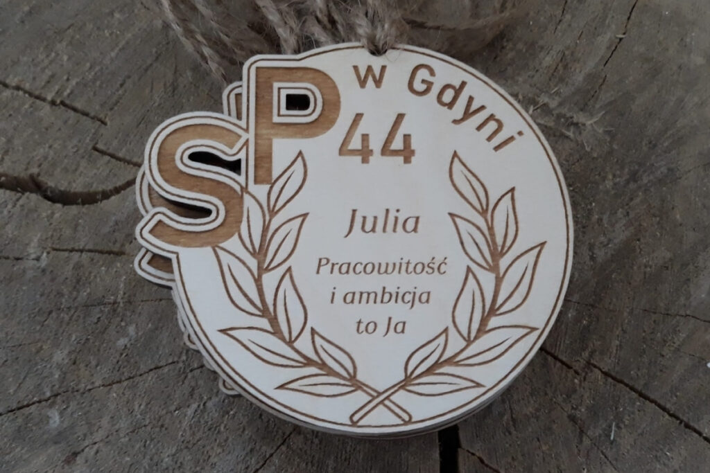 Okrągły drewniany medal na zakończenie roku szkolnego z personalizowanym grawerem imienia dziecka, krótkim tekstem o dziecku, wykonany z czystej brzozy bez osmaleń.