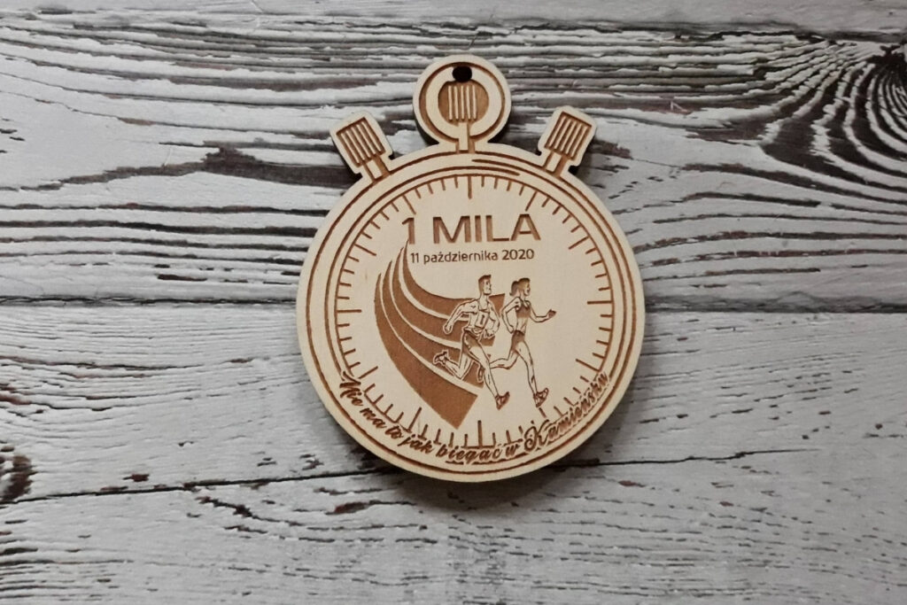 Drewniany medal w kształcie klasycznego stopera sportowego, z precyzyjnym grawerem tarczy zegara, przycisków funkcyjnych oraz miejscem na logo zawodów i datę, wykonany z czystej brzozy bez śladów osmaleń.