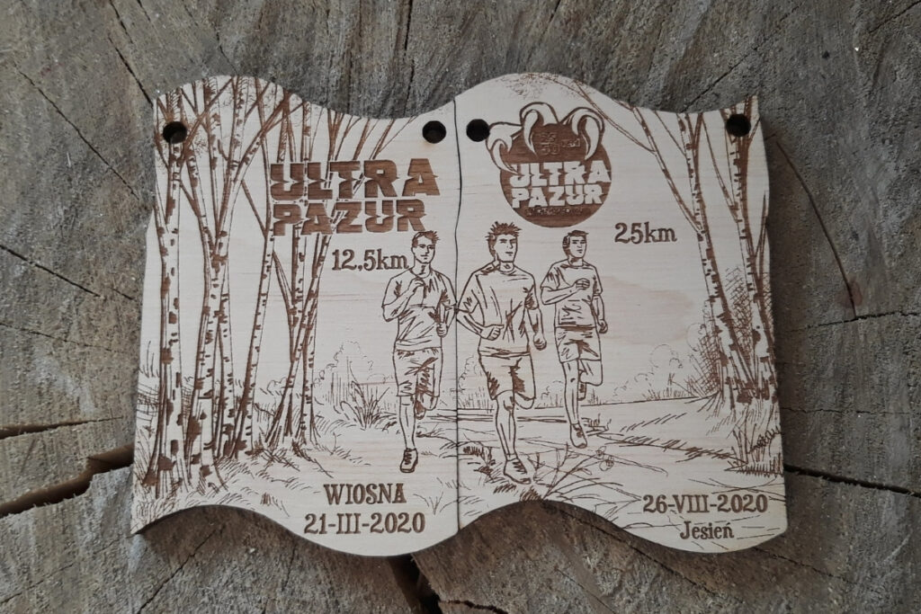 
Zestaw dwóch drewnianych medali modułowych na bieg Ultra Pazur, które po złożeniu tworzą spójną grafikę.