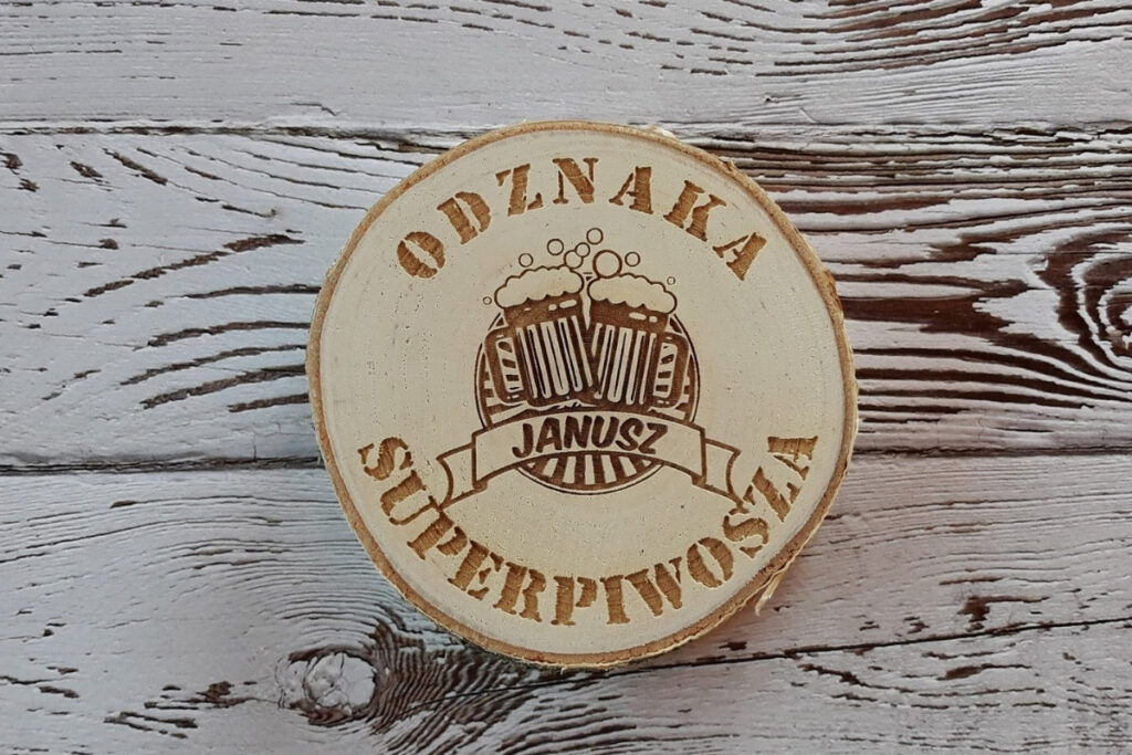 Drewniana podstawka pod piwo wykonana z naturalnego plastra brzozy z korą, z grawerem „Odznaka Superpiwosza”, motywem gwiazdy i kufla piwa, czysta powierzchnia bez osmaleń.