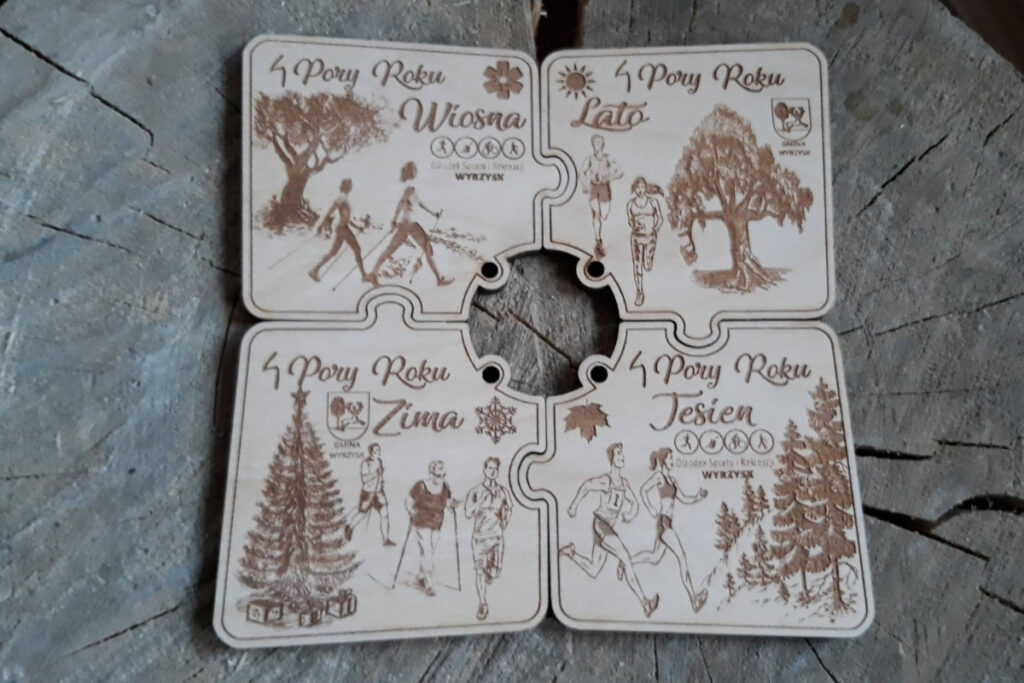 Zestaw czterech drewnianych medali modułowych z serii „4 Pory Roku”, które dzięki precyzyjnym wycięciom łączą się jak puzzle w jedną okrągłą tarczę, z grawerem płatków śniegu, słońca, liści i kwiatów, wykonany z czystej brzozy bez śladów dymu.