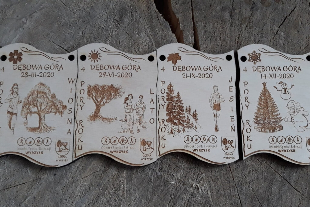 Zestaw czterech drewnianych medali modułowych z motywem „4 Pory Roku”, które łączą się w prostokątna tabliczkę za pomocą precyzyjnych wypustek - dopasowań, z grawerem motywów drzewa w 4 odsłonach pór roku, wykonane z czystej brzozy bez osmaleń.