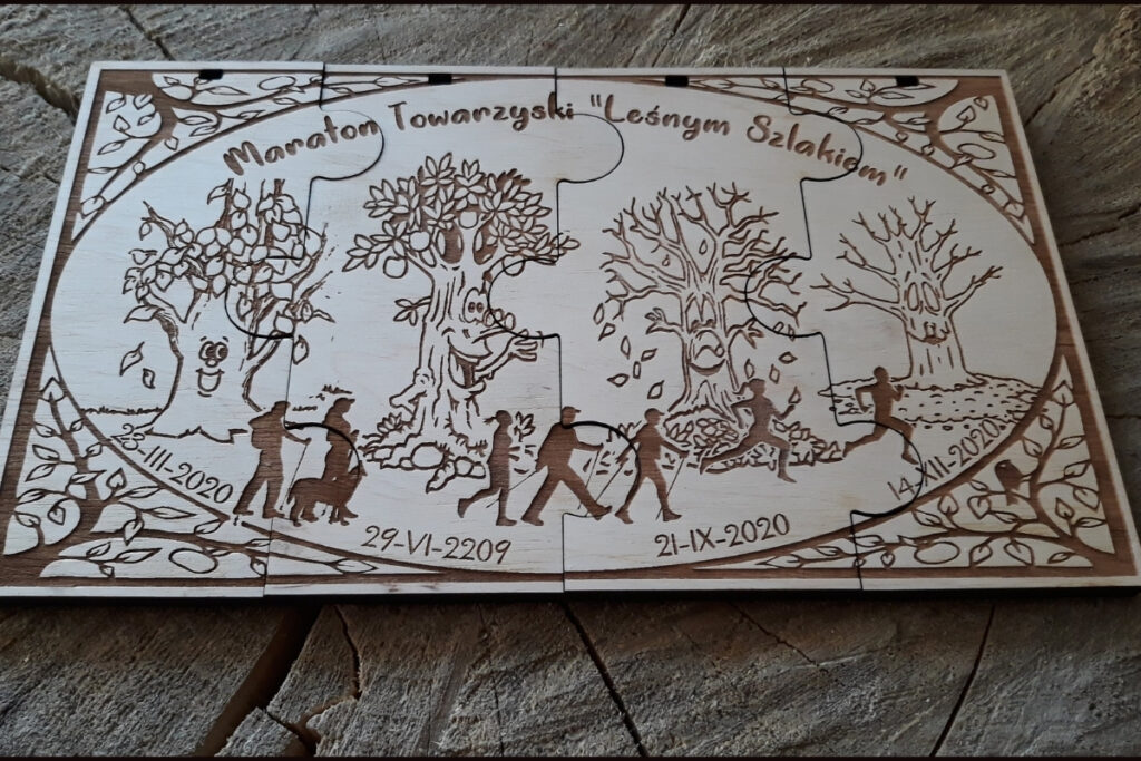 Zestaw czterech drewnianych medali modułowych na „Maraton Towarzyski”, które łączą się w jedną efektowną prostokątną tabliczkę za pomocą wypustek typu puzzle, z grawerem dat etapów i biegaczy oraz osób maszerujących Nordic Walking, wykonany z czystej brzozy bez osmaleń. Każdy etap przedstawia drzewo w innej odsłonie pory roku.