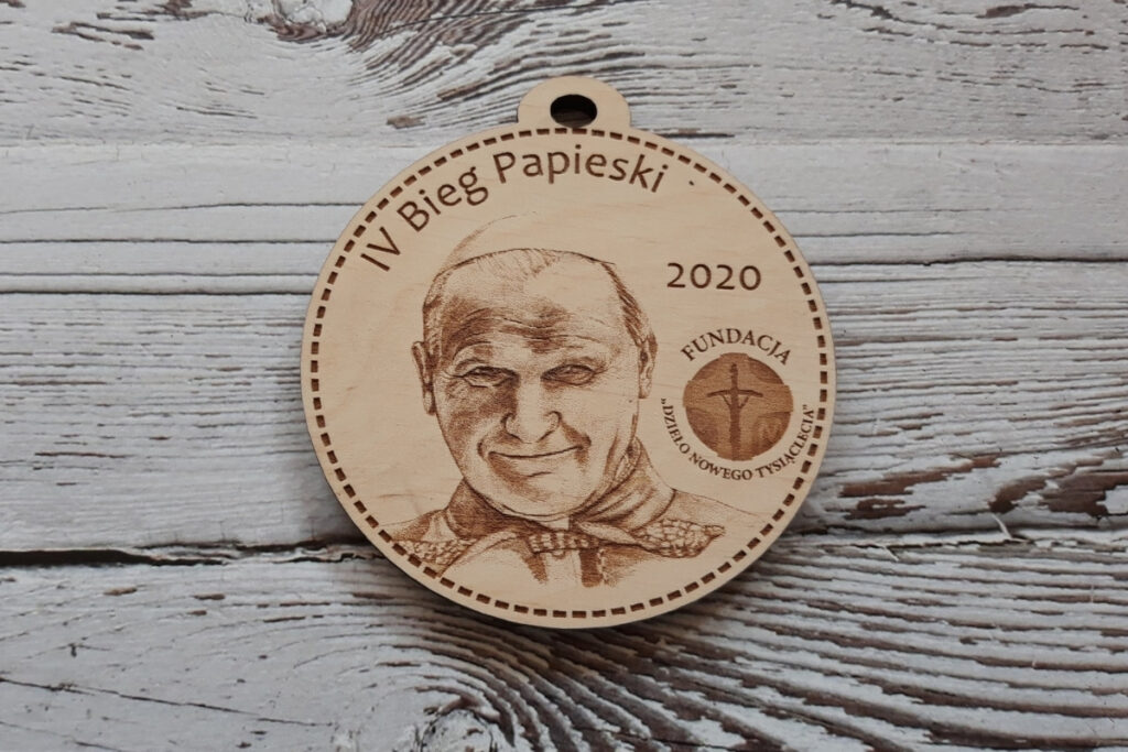 Okrągły drewniany medal grubości 6 mm wygrawerowany na sklejce liściastej z napisem IV Bieg Papieski, logiem i zdjęciem Jana Pawła II.