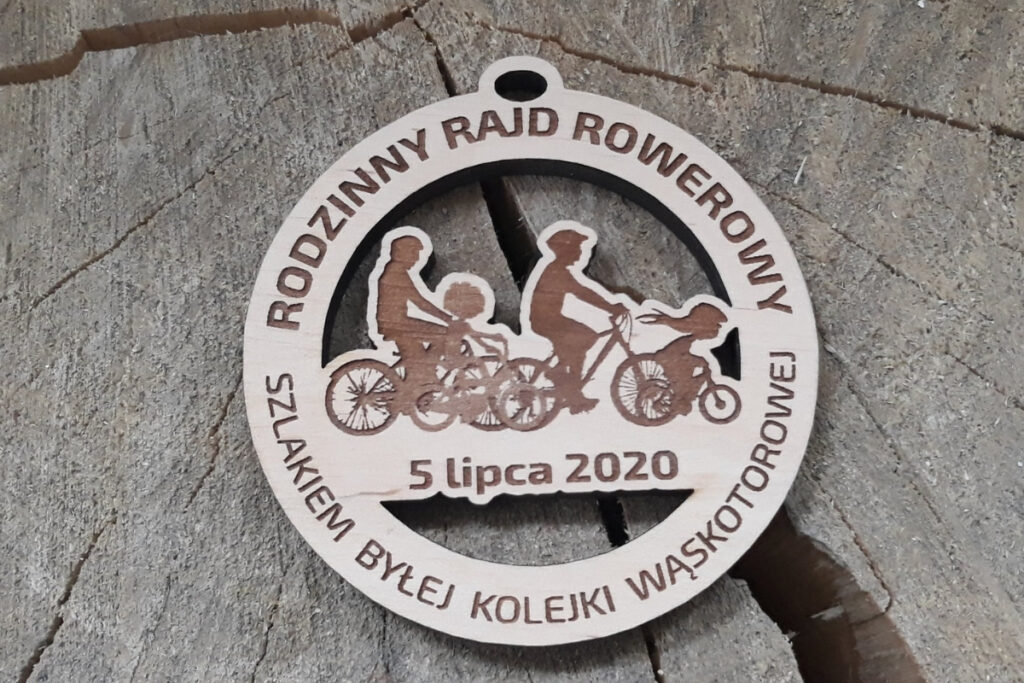 Ażurowy drewniany medal na „Rodzinny Rajd Rowerowy Szlakiem Byłej Kolejki Wąskotorowej”, z precyzyjnie wyciętymi sylwetkami rowerzystów, wykonany z czystej brzozy bez śladów osmaleń.. U góry kółko na zawieszenie karabińczyka, sznurka lub wstążki.