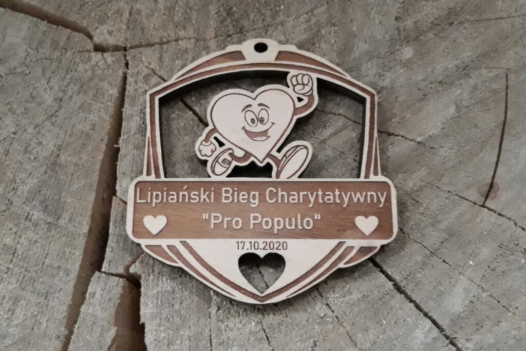 Ażurowy drewniany medal charytatywny z precyzyjnie wyciętym motywem biegnącego serca z nogami w butach sportowych, wykonany z jasnej brzozy o nieskazitelnie czystych krawędziach bez osmaleń.