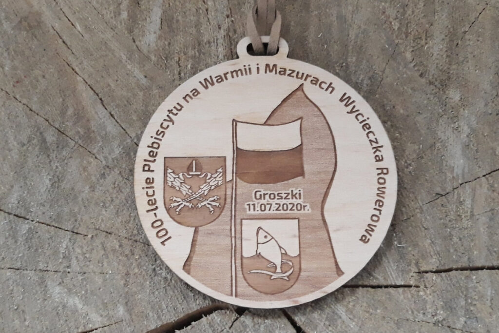 Okrągły drewniany medal upamiętniający 100-lecie Plebiscytu na Warmii i Mazurach.