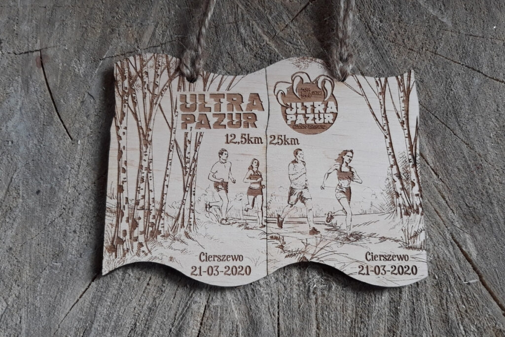 Zestaw dwóch drewnianych medali modułowych na bieg Ultra Pazur, które po złożeniu tworzą spójną grafikę.