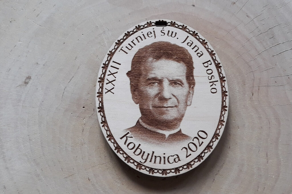 Owalny drewniany medal na „Turniej św. Jana Bosko”, z precyzyjnie wygrawerowanym wizerunkiem świętego, oraz napisem okolicznościowym, wykonany z czystej płyty brzozy bez śladów dymu i osmaleń.