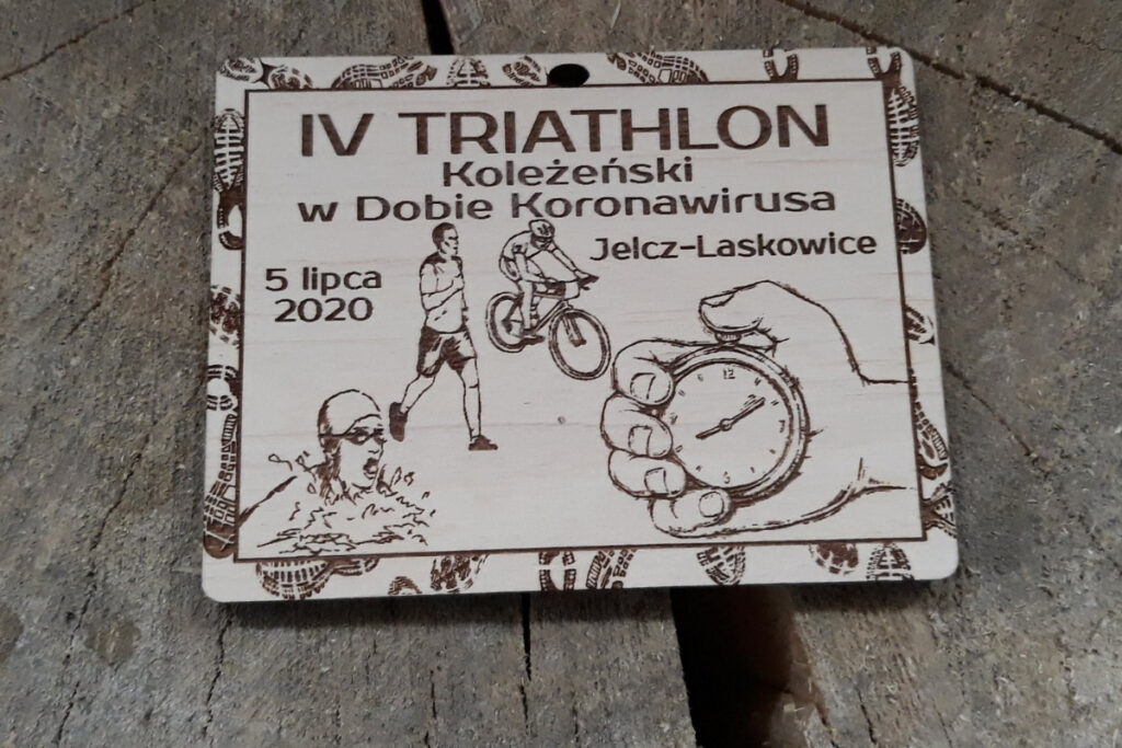 Prostokątny drewniany medal na „Triathlon Koleżeński”, z precyzyjnym grawerem trzech dyscyplin: pływania, kolarstwa i biegania, wykonany z jasnej brzozy o nieskazitelnie czystej powierzchni bez osmaleń. Na grafice także ręka trzymająca stoper.