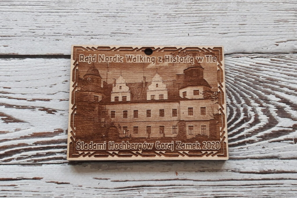 Prostokątny drewniany medal z fotorealistycznym grawerem Zamku w Goraju, upamiętniający rajd „Śladami Hochbergów”, wykonany z jasnej brzozy o nieskazitelnie czystej powierzchni bez osmaleń.
