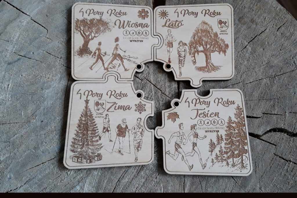 Zestaw czterech drewnianych medali modułowych z serii „4 Pory Roku”, które dzięki precyzyjnym wycięciom łączą się jak puzzle w jedną okrągłą tarczę, z grawerem płatków śniegu, słońca, liści i kwiatów, wykonany z czystej brzozy bez śladów dymu.