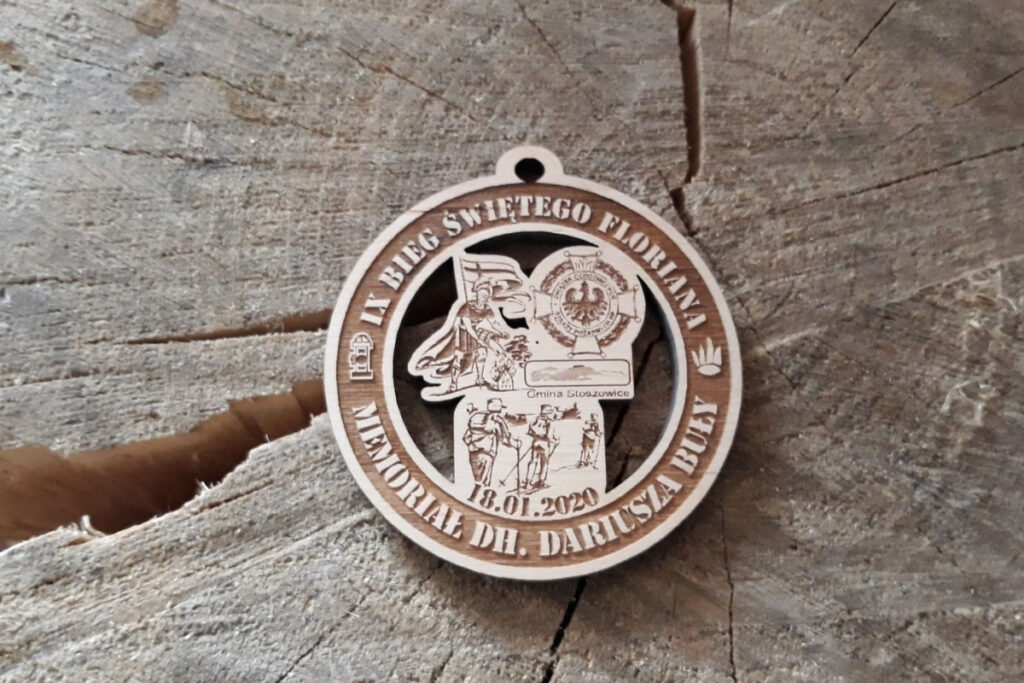 Okrągły ażurowy drewniany medal na Bieg Narciarski Świętego Floriana z precyzyjnym grawerem narciarzy i logotypów.