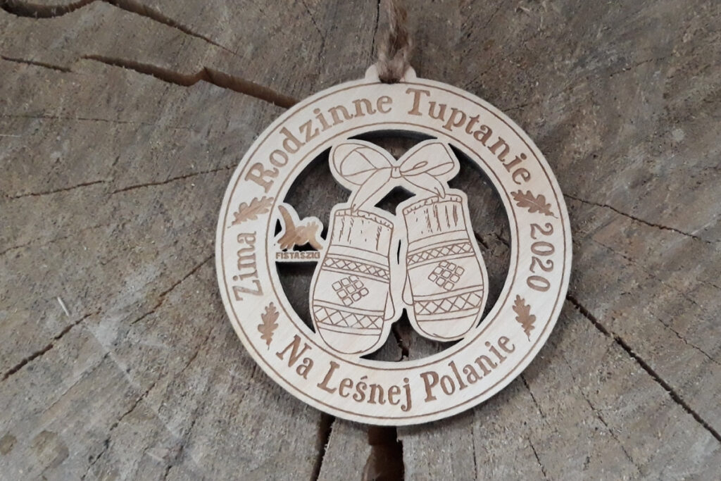 Ażurowy drewniany medal na Rodzinne Tuptanie z precyzyjnie wyciętym motywem zimowych rękawiczek.
