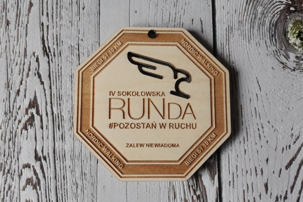 Nowoczesny ośmiokątny drewniany medal z precyzyjnie wyciętym ażurowo logotypem wydarzenia.