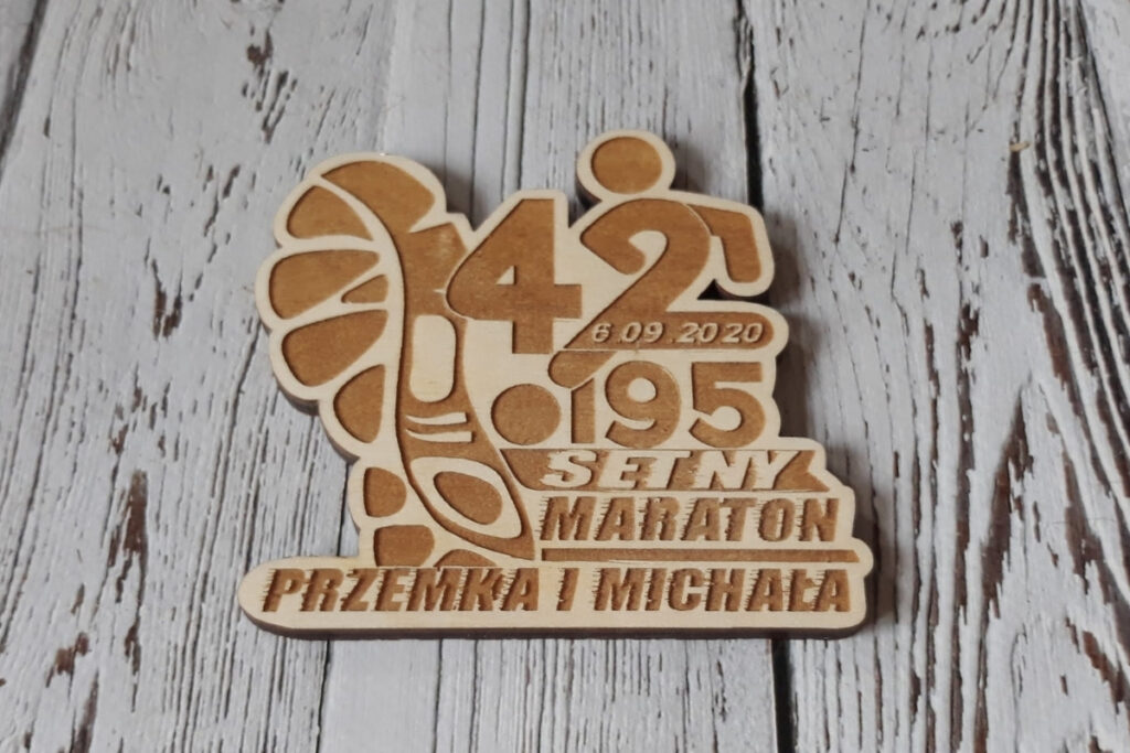 Wyjątkowy drewniany medal jubileuszowy na setny maraton z grawerem maratończyka wpisanym w cyfrę 42,195.