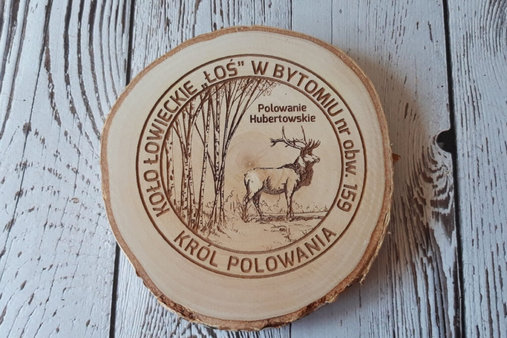 Naturalny medal na plastrze brzozy z korą i grawerem jelenia pośród brzózek, przygotowany dla Króla Polowania.