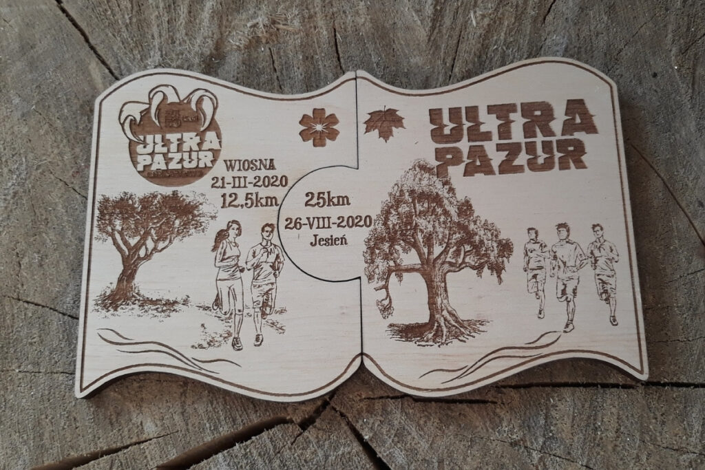 Zestaw dwóch drewnianych medali modułowych na bieg Ultra Pazur, które po złożeniu tworzą spójną grafikę.
