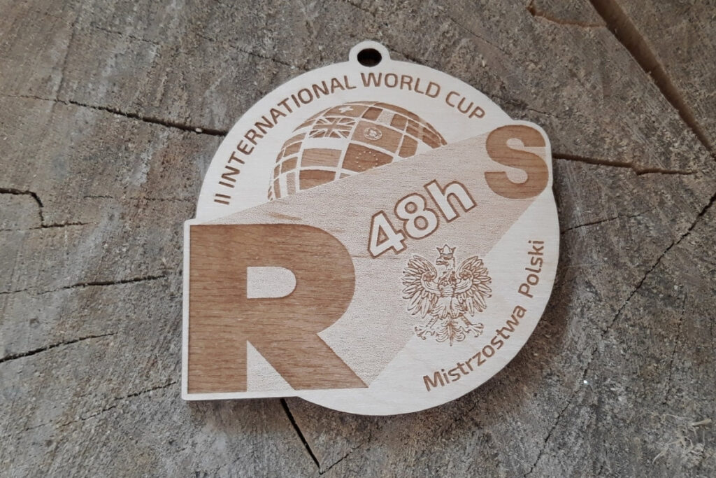 Okrągły drewniany medal na zawody II International World Cup z grawerowanym logotypem mistrzostw i eleganckimi detalami.