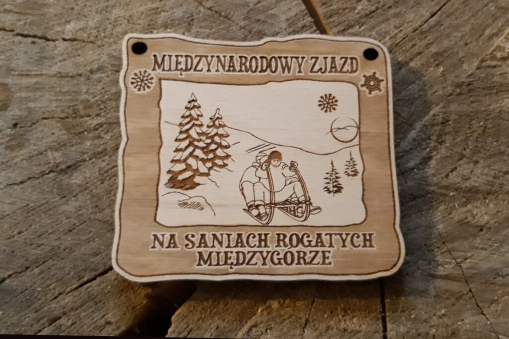 Prostokątny drewniany medal na tradycyjny Zjazd na Saniach Rogatych z grawerem sani rogatychi zimowym motywem górskim.