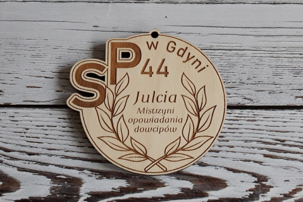 Okrągły drewniany medal na zakończenie roku szkolnego z personalizowanym grawerem imienia dziecka, krótkim tekstem o dziecku, wykonany z czystej brzozy bez osmaleń.